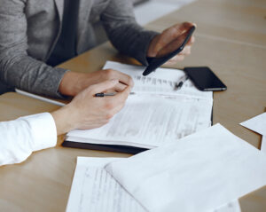 Business men sitting at the lawyers's desk. People signing important documents.